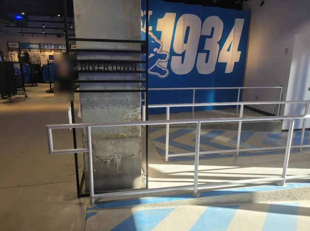 Silver steel handrails and a black steel cage around a column inside the Detroit Lions team store