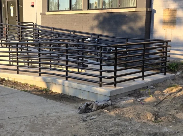 Black steel ramp railing and handrails built by Xcellent Services along the entrance of an apartment building